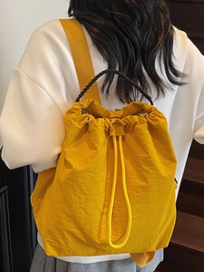 Water-repellent yellow drawstring backpack with top handle and woven shoulder straps
