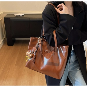 Close-up of glossy brown tote bag with metal logo, cute bear and star pendants