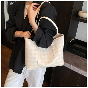 Close-up of beige checkered tote bag on a model showing large capacity for daily commuting