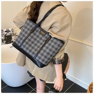 Back view of a model carrying a large checkered tote bag with black leather straps