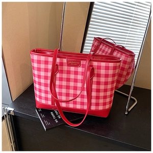 Detailed view of the red and pink plaid tote bag texture and brand logo metal plate