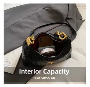 Detail view of large capacity black quilted bag with red lining and golden hardware