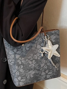Fashionable floral print tote bag with brown leather handles and decorative charms