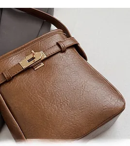 Detailaufnahme der braunen Ledertasche mit Litschi-Muster und goldenem Drehverschluss