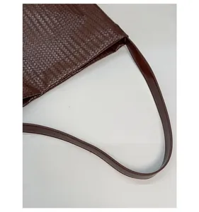 Détail de la texture tressée marron et de la bandoulière en cuir confortable sur un sac seau