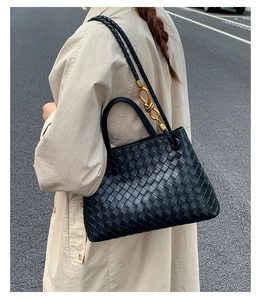Detail of woven leather handbag featuring intricate weave and iconic gold metal buckle knot