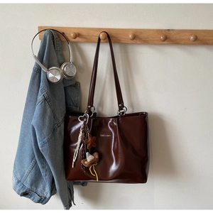 Deep brown glossy faux leather tote bag detail with star and bear plush charms