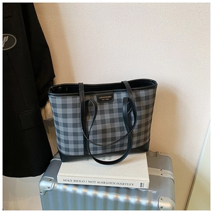 Detail of grey and black checkered tote bag with LUOIEMSINAH logo and leather handles