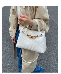 Detail of white woven leather handbag featuring a gold knot clasp and fine shoulder strap