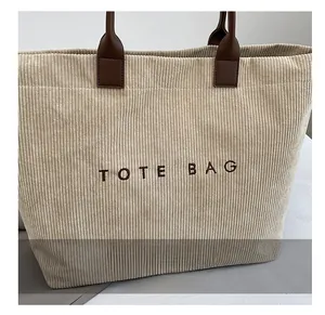 Detailed close-up of corduroy tote bag texture with brown TOTE BAG embroidery