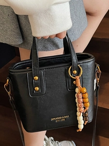 Schicke schwarze Beuteltasche mit Perlenanhänger auf hölzernem Hintergrund