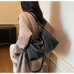 Detailed view of large black leather hobo bag with silver buckles and lychee grain texture