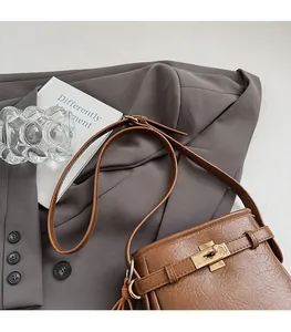 Detailansicht der braunen PU-Ledertasche mit goldenem Drehverschluss und Quasten-Anhänger