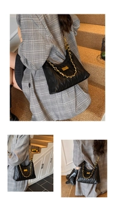 Detailed macro view of quilted black leather texture and golden metal chain strap