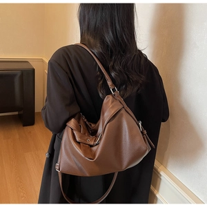 Detail of dark brown pebble leather tote bag with metallic buckle and shoulder strap