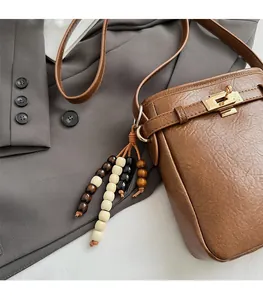 Detailaufnahme der braunen Bucket Bag mit Litschimuster, Goldverschluss und Perlenquaste