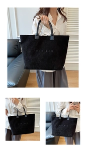 Detailed close-up of a black corduroy tote bag with embossed text and leather handles