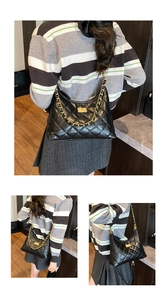 Detail view of the black quilted tote bag with gold chain strap on a model's shoulder