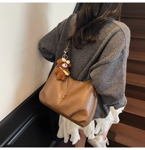 Sac fourre-tout en cuir marron avec charme d'ours sur un mannequin dans un escalier