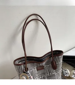 Detail of geometric pattern tote bag with leather strap and straw hat charm