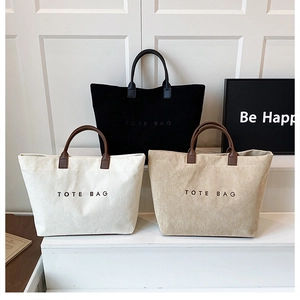 Three corduroy tote bags in black, white, and beige with brown leather handles