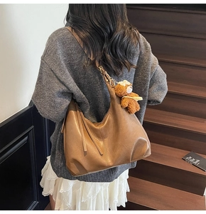 Détail d'un grand sac hobo marron avec un pendentif ours et des pampilles de fermeture éclair