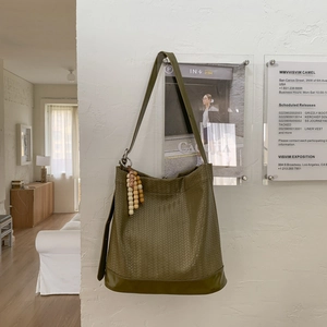 Gros plan sur la texture tissée verte et le pompon en perles de bois sur le sac seau
