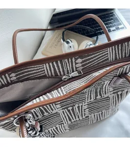 Close-up of metal zipper and leather handle on a large woven tote bag for office work