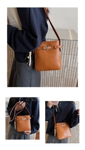 Detail der karamellfarbenen Eimer-Tasche mit goldenem Drehverschluss und Perlenanhänger