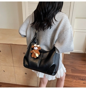 Vue arrière d'un grand sac hobo noir minimaliste avec un joli pendentif ours en peluche