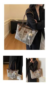 Detail of the woven tote bag showing leather handles and unique straw hat charm
