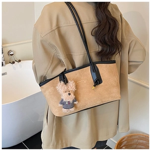Detail of a brown suede tote bag with black leather trim and a cute puppy charm