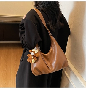 Vue détaillée d'un sac hobo demi-lune marron avec un pendentif ours en peluche mignon