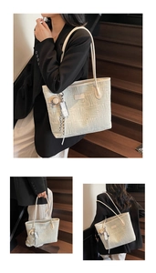 Detail of woven tote bag featuring white leather handles and mini straw hat charm decoration