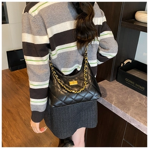 Detailed view of black quilted crossbody bag with gold chain and metal twist lock