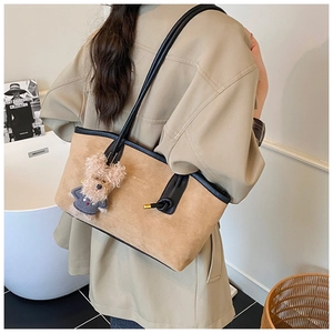 Detail of suede tote bag with leather straps and a cute plush puppy pendant