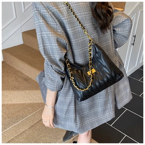 Detail of black quilted leather shoulder bag with gold chain strap and metal lock