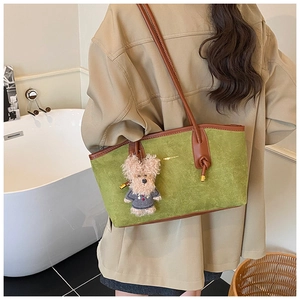Detail of green suede tote bag with brown leather handles and a cute puppy plush charm