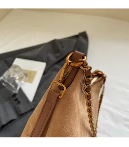 Detailed macro shot of vintage gold chain strap and matte metal hardware on brown bag