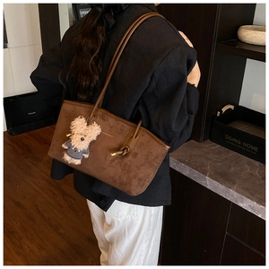 Detail view of deep brown suede tote bag with cute plush puppy charm accessory