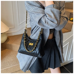 Detail of black quilted leather shoulder bag with gold chain strap and metal turn-lock