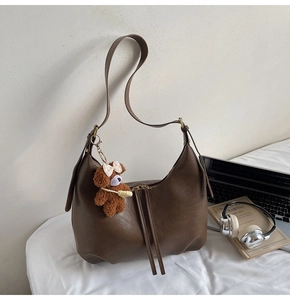 Détail du sac hobo avec pompon en cuir et breloque ours en peluche dans un décor chic
