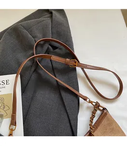 Detail of vintage brown leather bag with adjustable strap and gold chain accessories