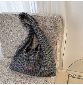 Detail of checkered canvas tote bag with vintage leather patch on a soft sofa