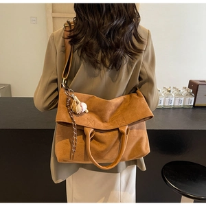 Détail d'un sac à bandoulière en daim marron avec breloques baseball et bandoulière