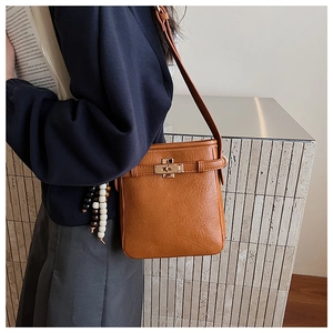 Detail der braunen Tasche mit Litschi-Muster, goldener Schließe und Perlen-Quaste