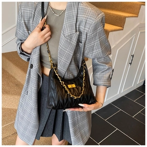 Close-up of quilted black shoulder bag with V-shaped texture and gold chain strap