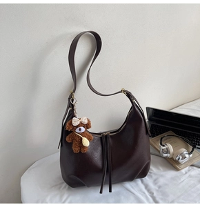 Détail d'un sac hobo marron vintage en similicuir lisse avec un joli porte-clés ours