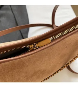 Detail of vintage gold zipper and matte brown suede texture on a chic shoulder bag