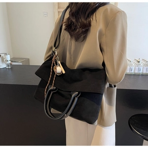 Detailed view of black canvas tote bag with adjustable strap and baseball charm
